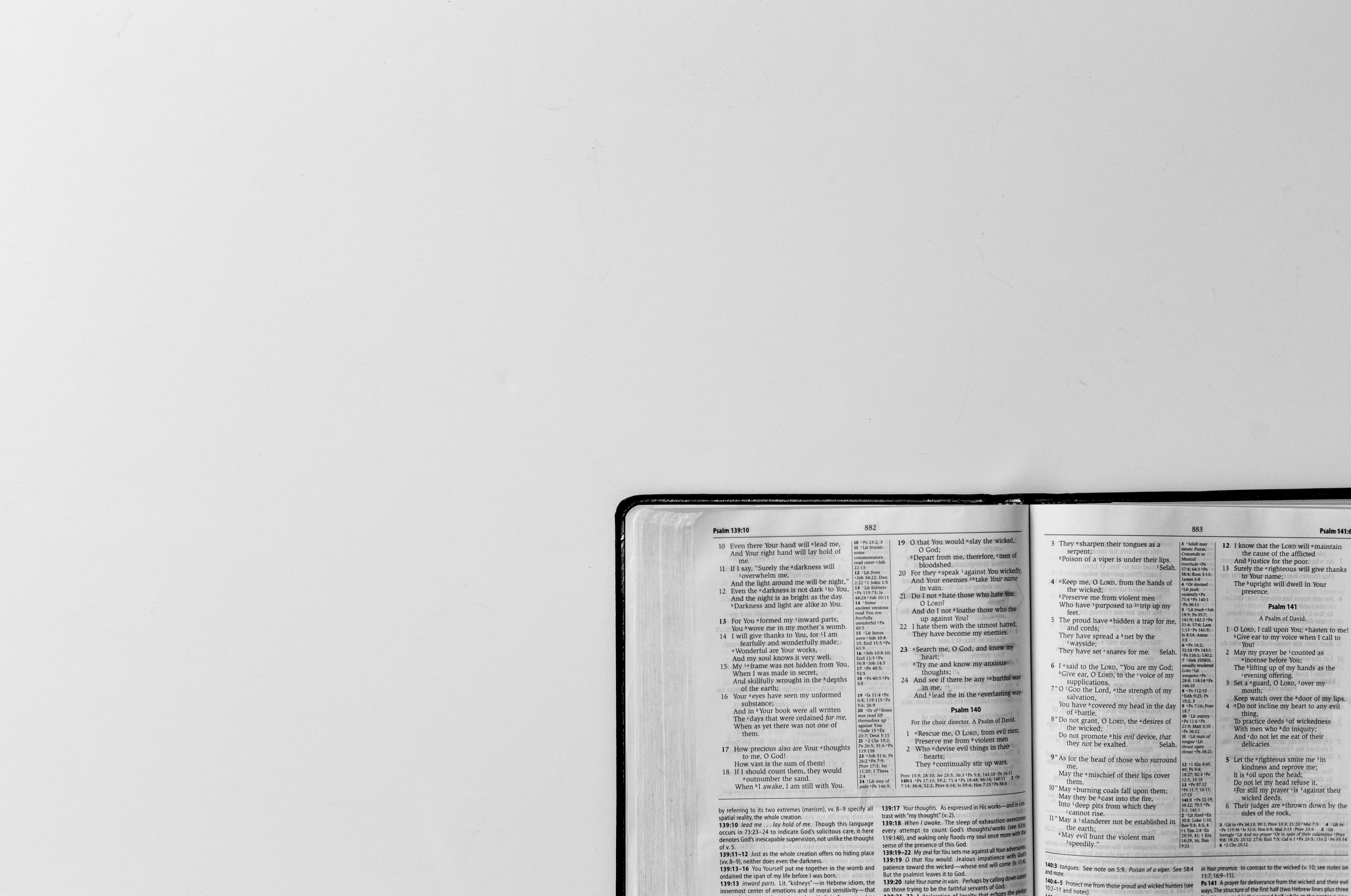 Eine aufgeschlagene Bibel mit schwarzem Einband im Anschnitt auf weißem Grund. Zu sehen ist eine Doppelseite aus dem Psalter in englischer Sprache
